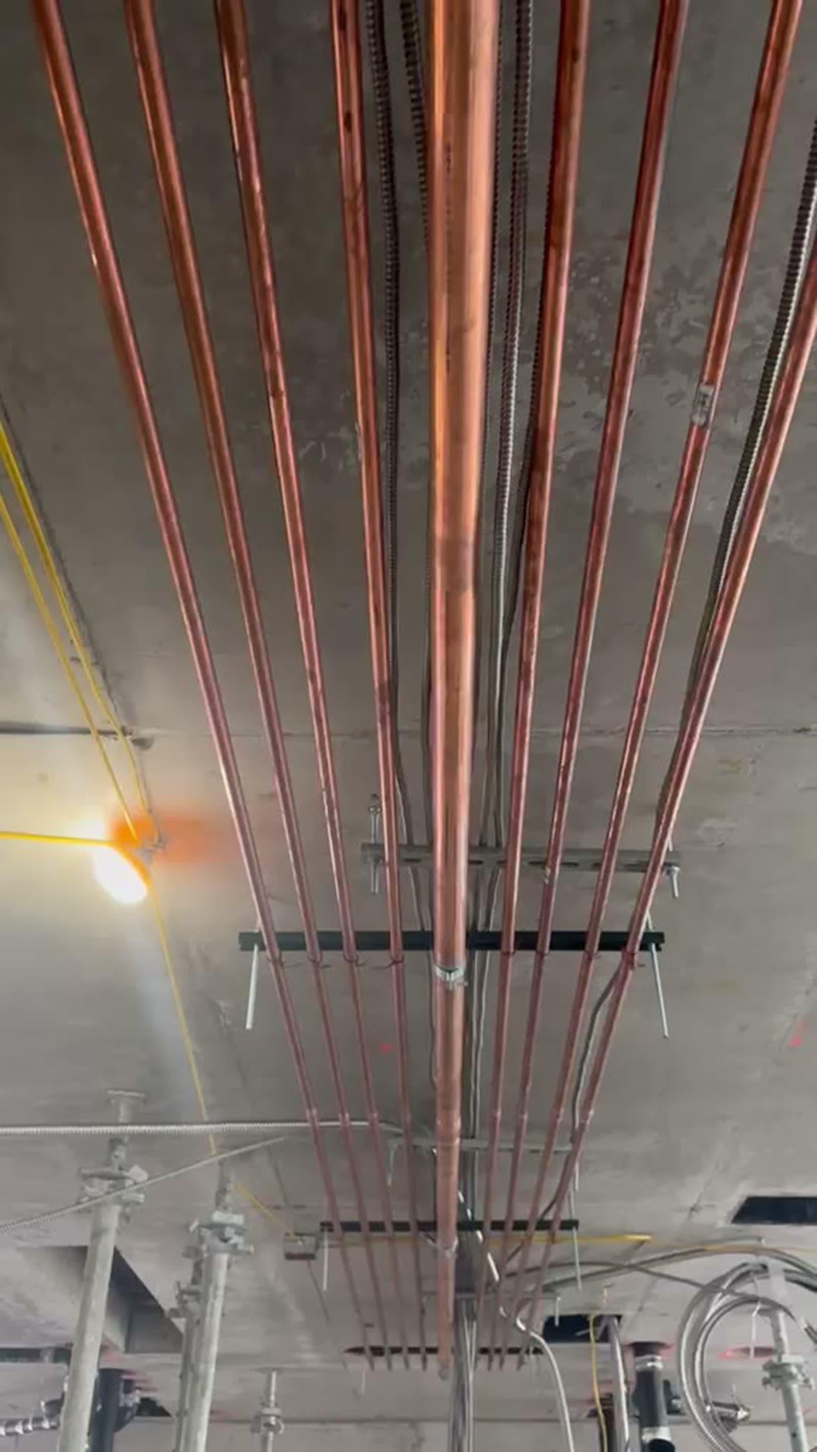 Overhead copper water mains and cast-iron drainage installed by EMC Plumbing on a commercial floor
